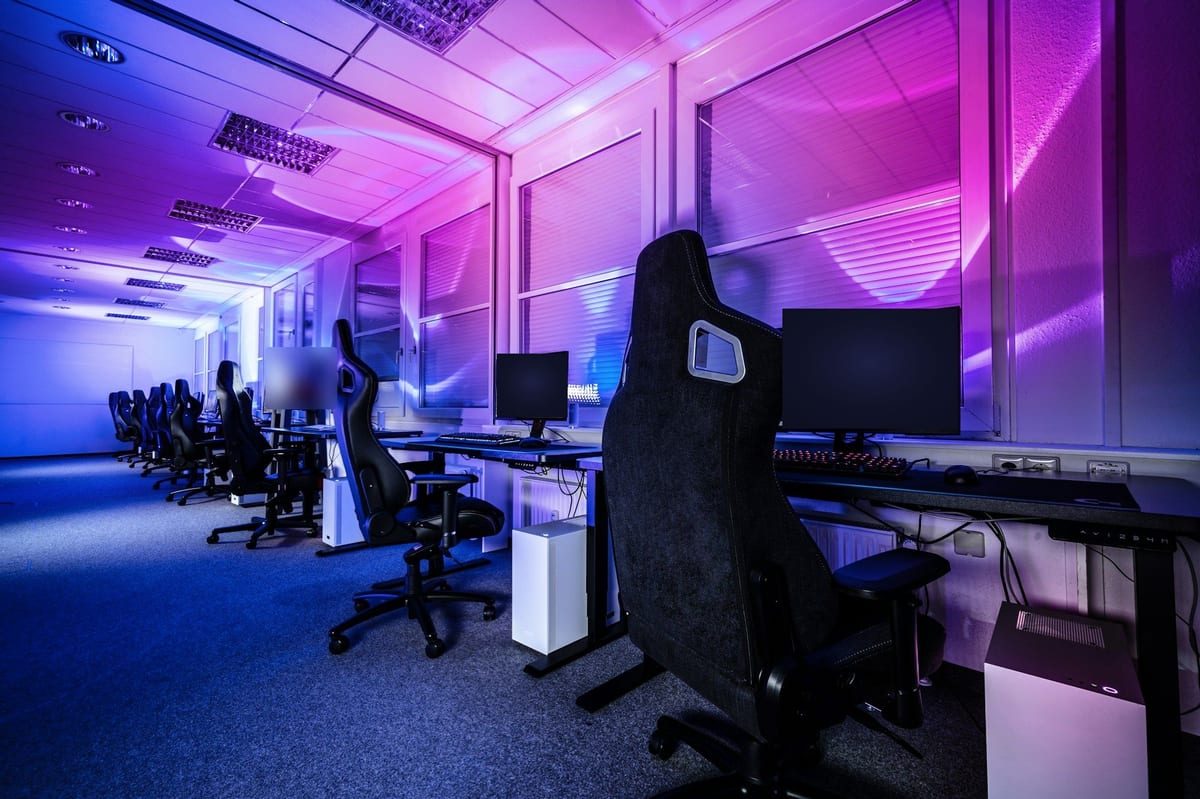 Esports training room: rows of gaming stations and chairs under purple lighting
